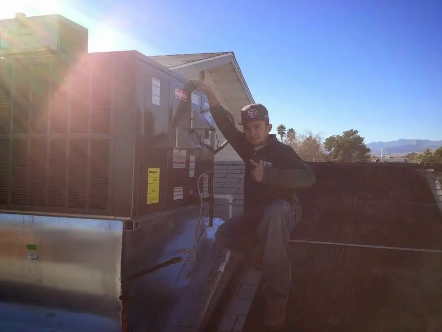HVAC technician performing Heat Pump Repair on a rooftop unit in Walton